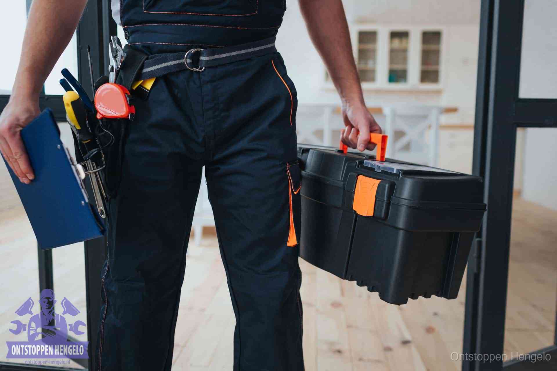 Een monteur met gereedschapsriem en klembord in een keuken, klaar om een transparante prijs voor het gootsteen ontstoppen in Hengelo te geven
