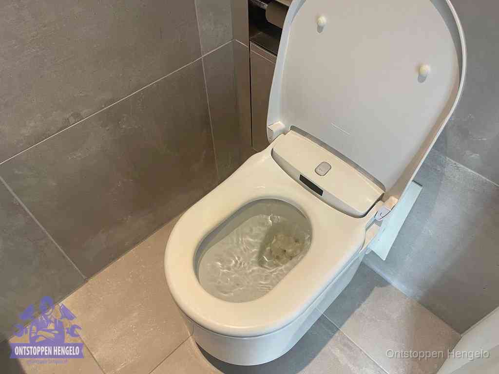 Een toiletpot vol troebel water met drijvend papier en restanten, de meest voorkomende oorzaak van een verstopte wc in Hengelo