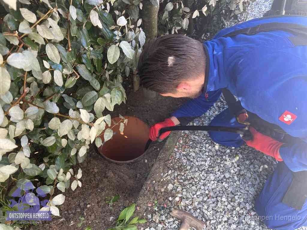 Monteur reinigt een rioolput met een slang, periodieke rioolreiniging in Hengelo