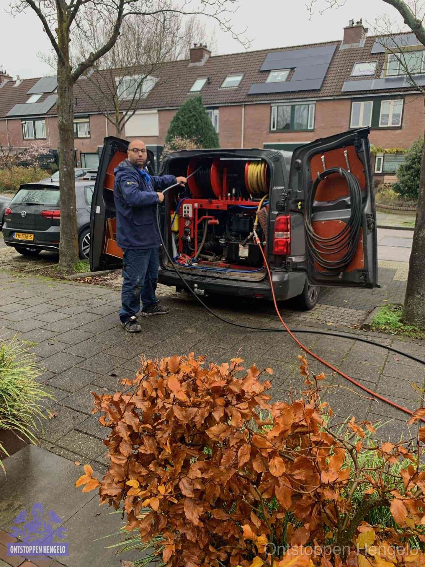 Monteur met rioolreinigingsbus levert rioolservice in de wijk in Hengelo