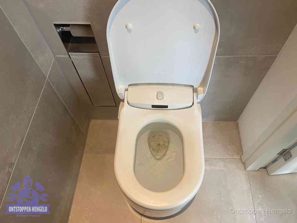 Een wit hangtoilet waarin een prop wc-papier op het water blijft drijven, een duidelijk signaal van een verstopte wc in Hengelo