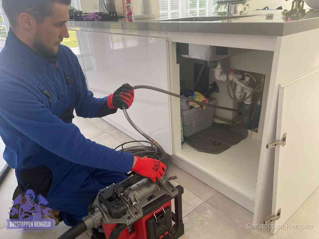 Een monteur reinigt de keukenafvoer grondig met een veermachine om terugkerende gootsteenverstoppingen te voorkomen in Hengelo